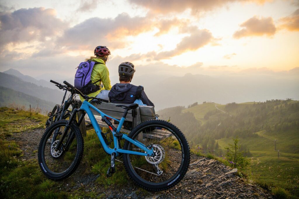 2 junge Mountainbiker genießen die Aussicht vom Gipfel eines Berges in Altenmarkt-Zauchensee