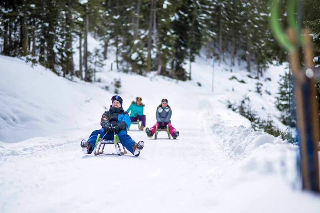 Ein Gruppe von Personen beim Rodeln auf einer Rodelbahn während Winterurlaub Altenmarkt Zauchensee