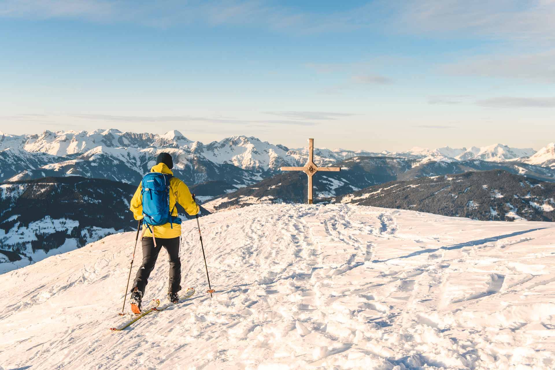 Ein Skitourengeher beim Gipfelkreuz des Lackenkogel, einem Berg in der Nähe von Altenmarkt-Zauchensee