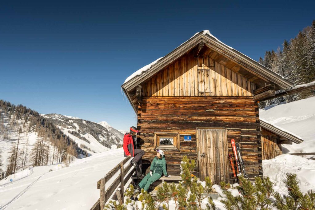 Ein Pärchen macht bei einer Hütte in Altenmarkt-Zauchensee ein kleine Pause vom Skifahren